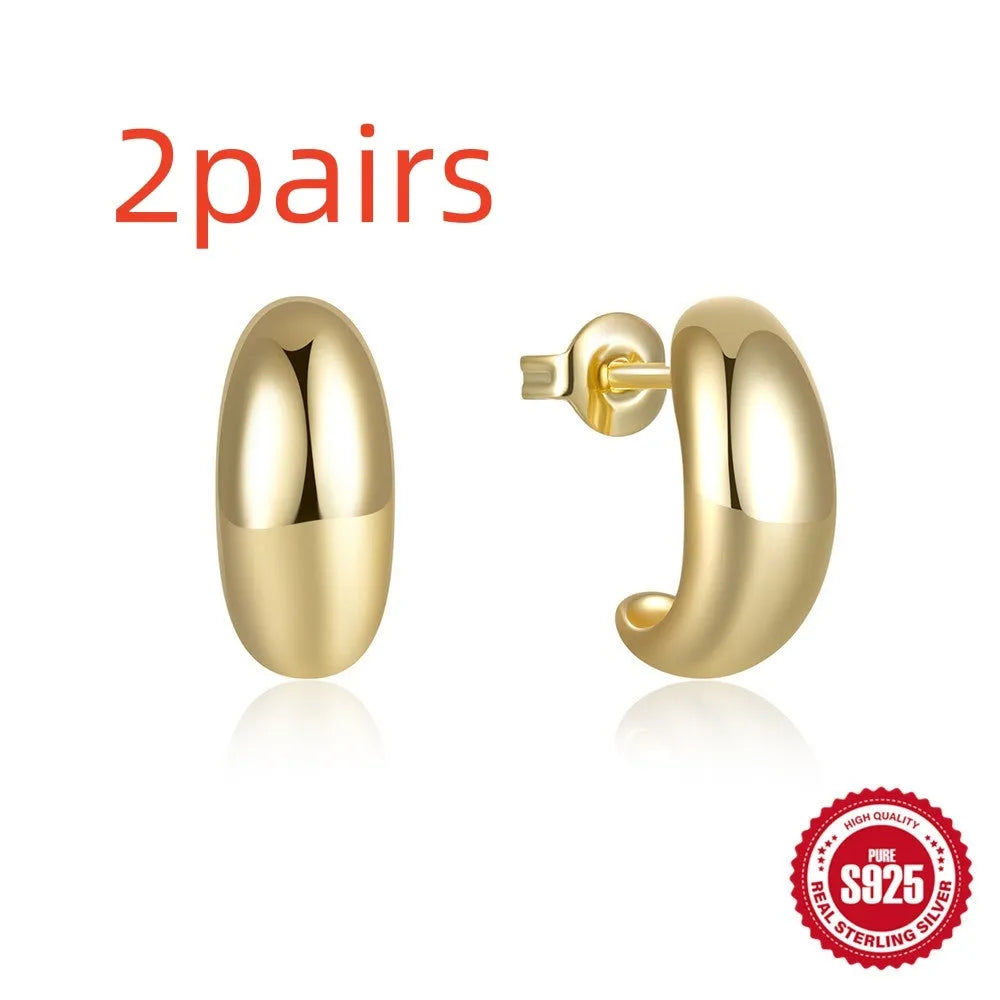 Close-up of a glossy C-shaped sterling silver stud earring in a gold electroplated finish.