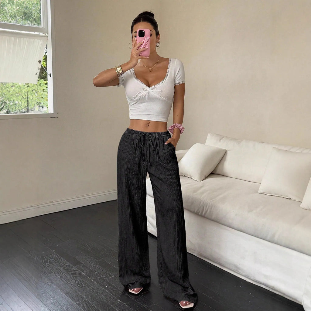 Black wide-leg women's trousers with a front lace-up waist detail on a neutral background.