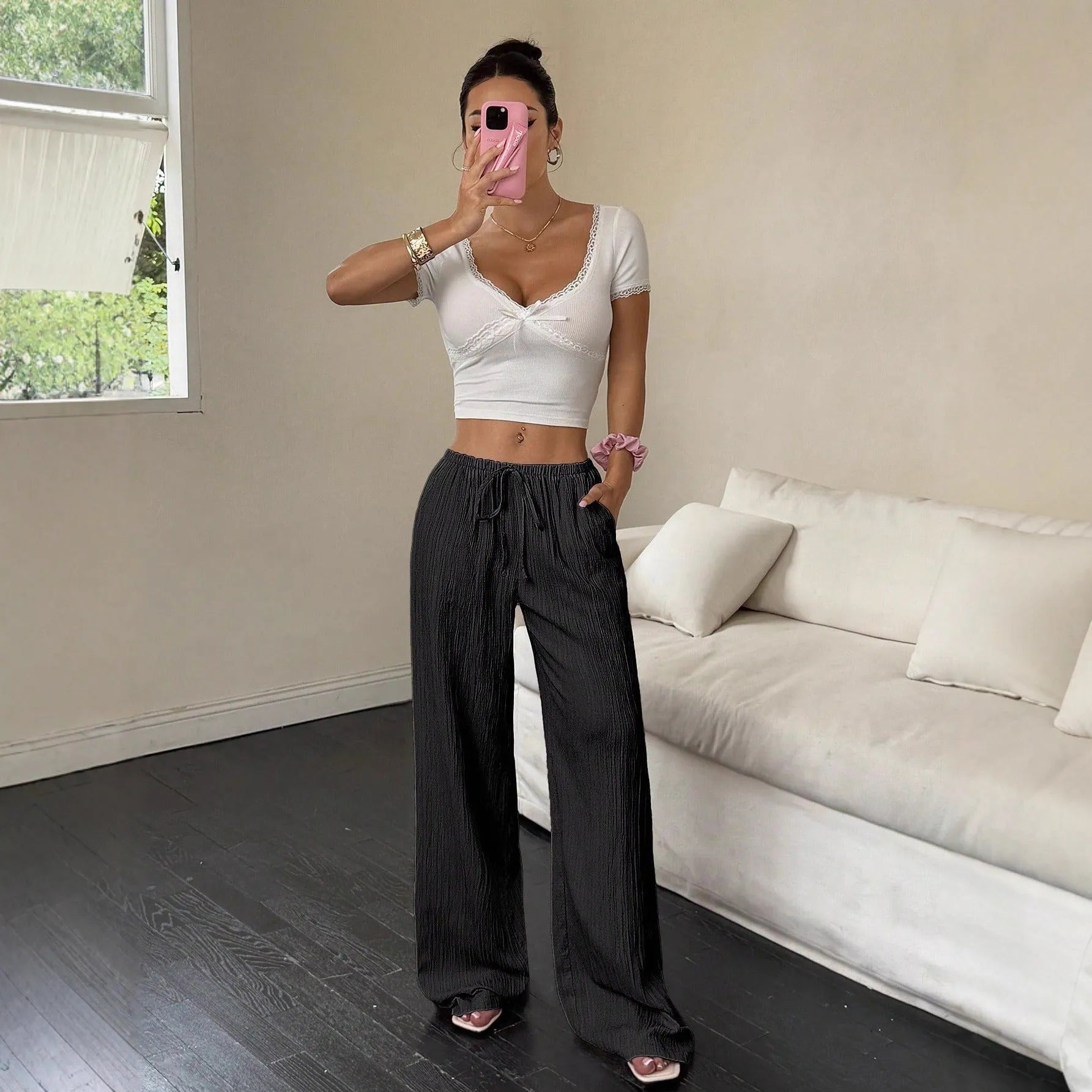 Black wide-leg women's trousers with a front lace-up waist detail on a neutral background.