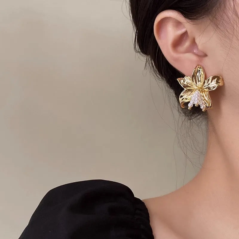 Gold H1795 metal flower earrings with an exaggerated floral design and pearl details.