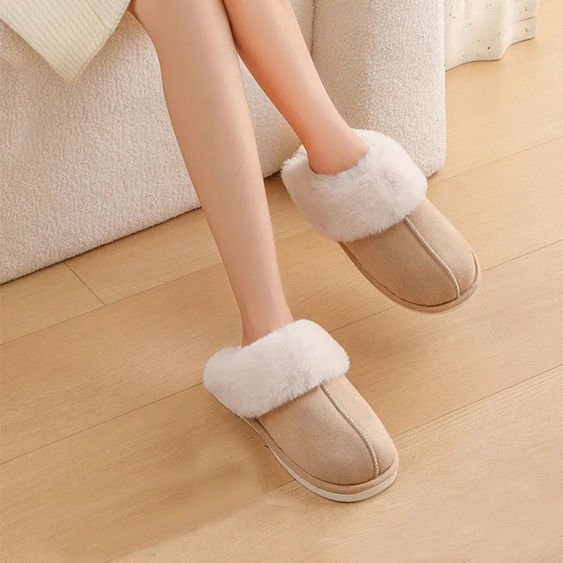 Brown plush indoor slippers for women with a non-slip PVC sole on a wooden floor.
