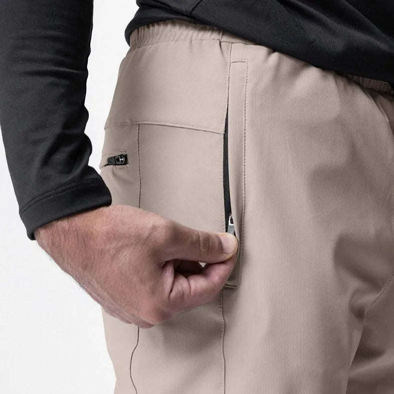 Man wearing dark grey loose-fit fitness trousers with tied ankles, made of quick-dry polyester blend fabric.