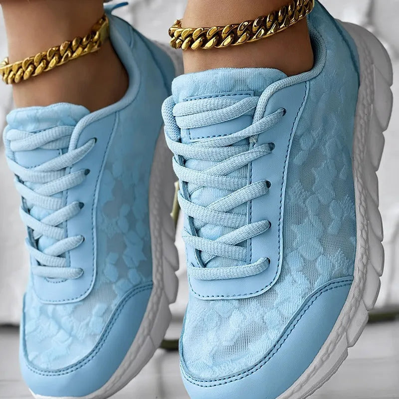 Women's white canvas running shoes with a flat heel and soft sole on a plain background.