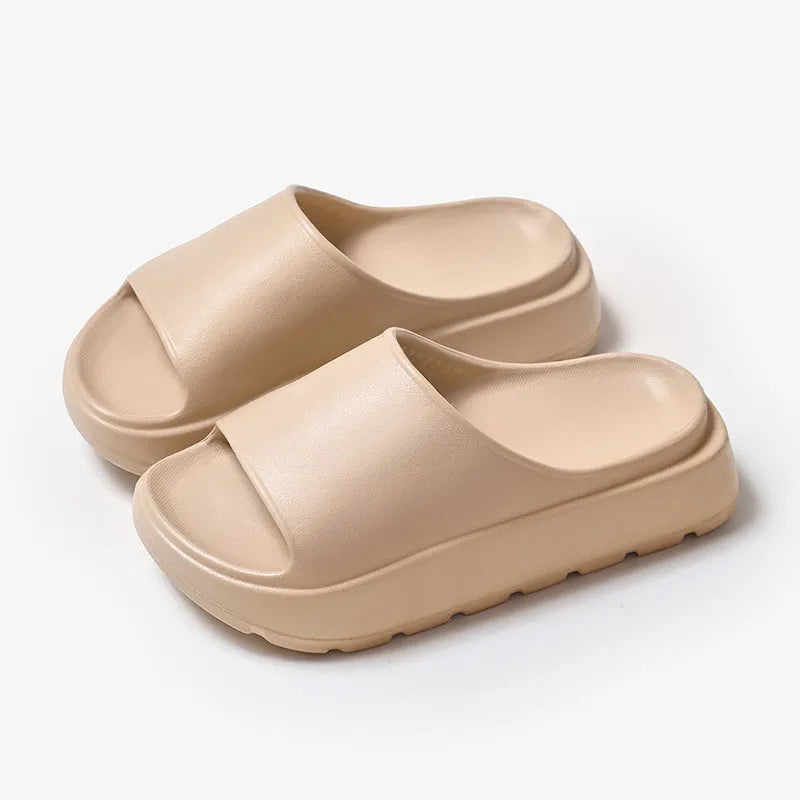 Women's beige thick-soled EVA beach slippers with fish mouth design on a wooden floor.