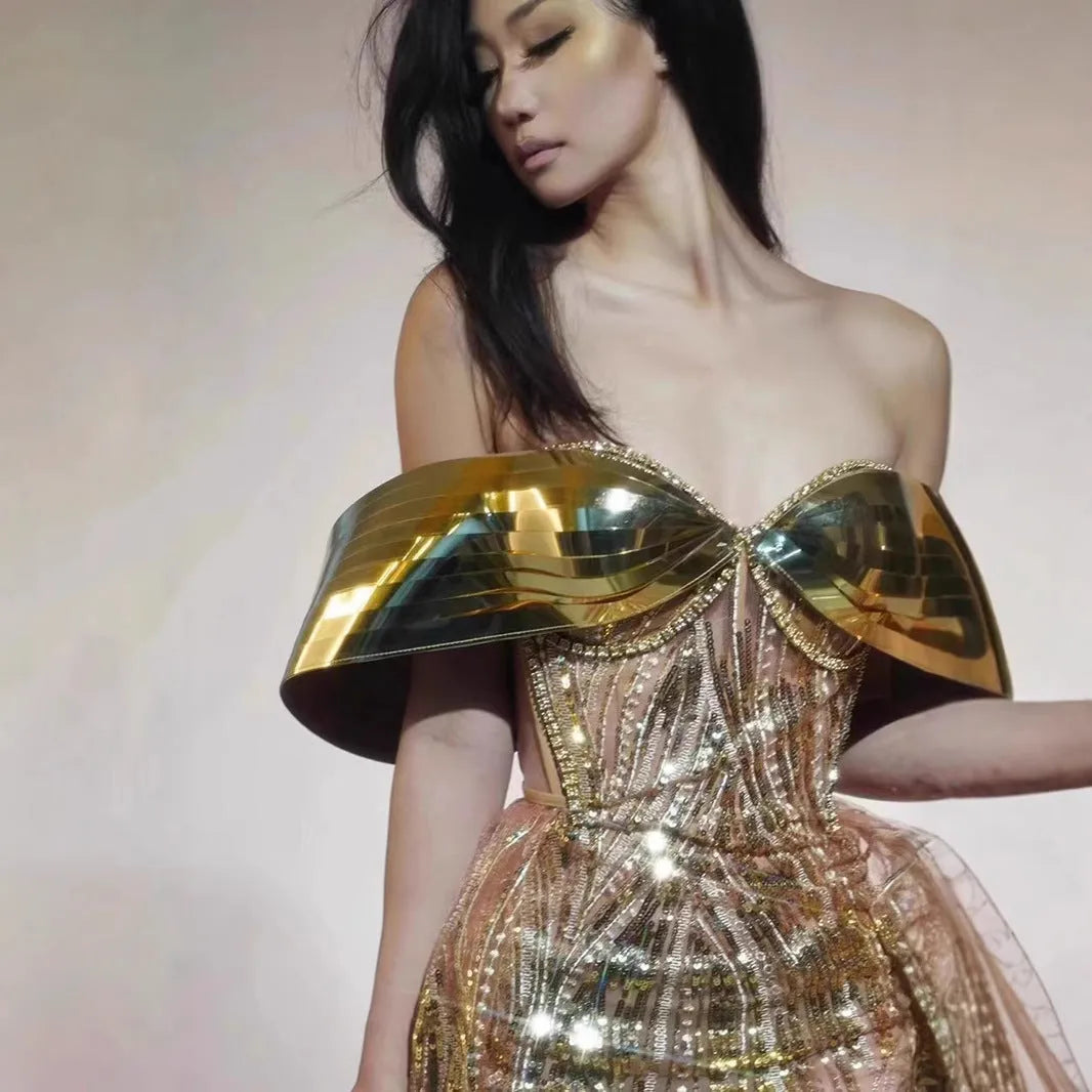 Gold strapless sequin evening dress with a long tulle skirt and thigh split on a mannequin.
