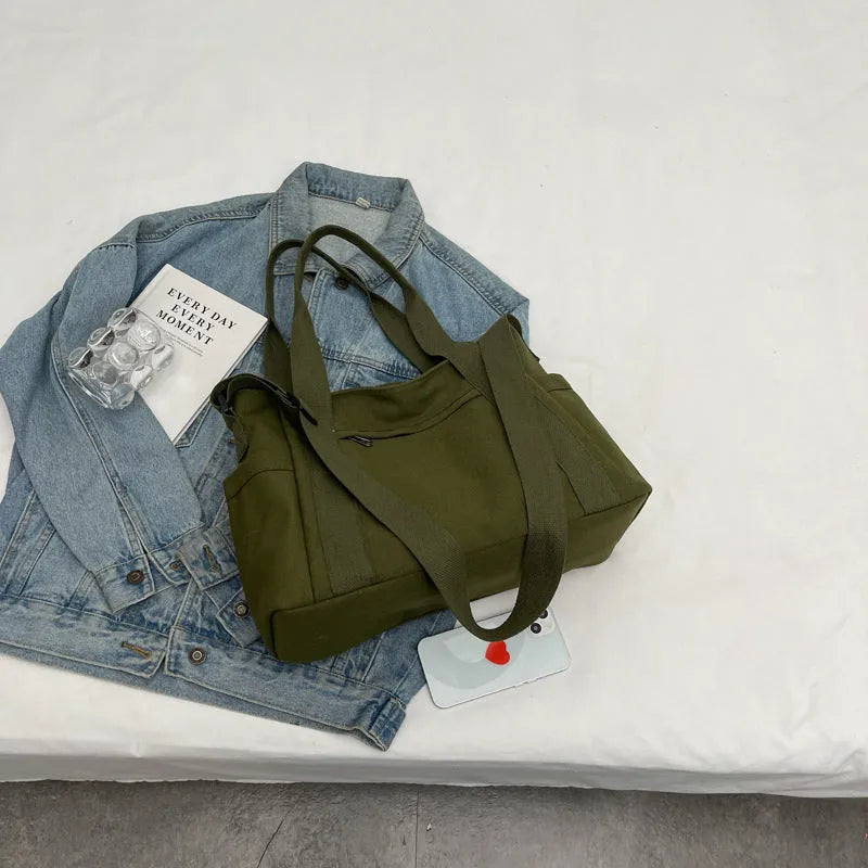 Large solid colour polyester canvas shoulder bag for women showing external pocket and strap.
