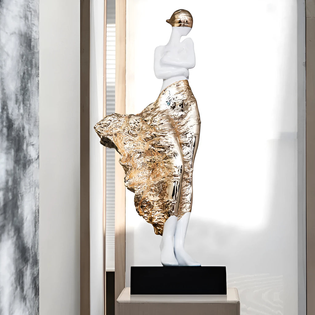Tall modern sculptured character ornament in a metallic rose gold finish on a table.
