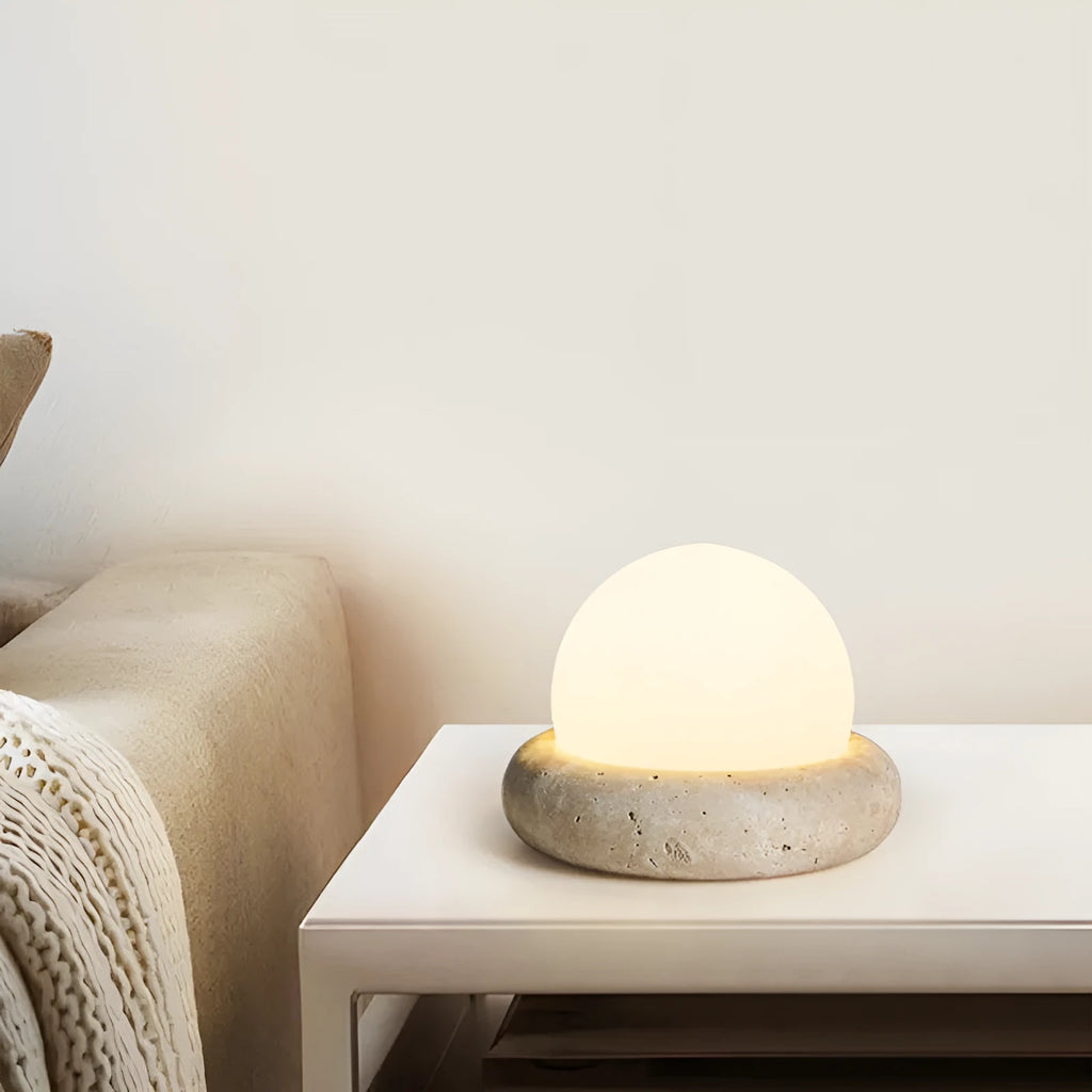 Circular modern night light with remote control on a wooden bedside table.