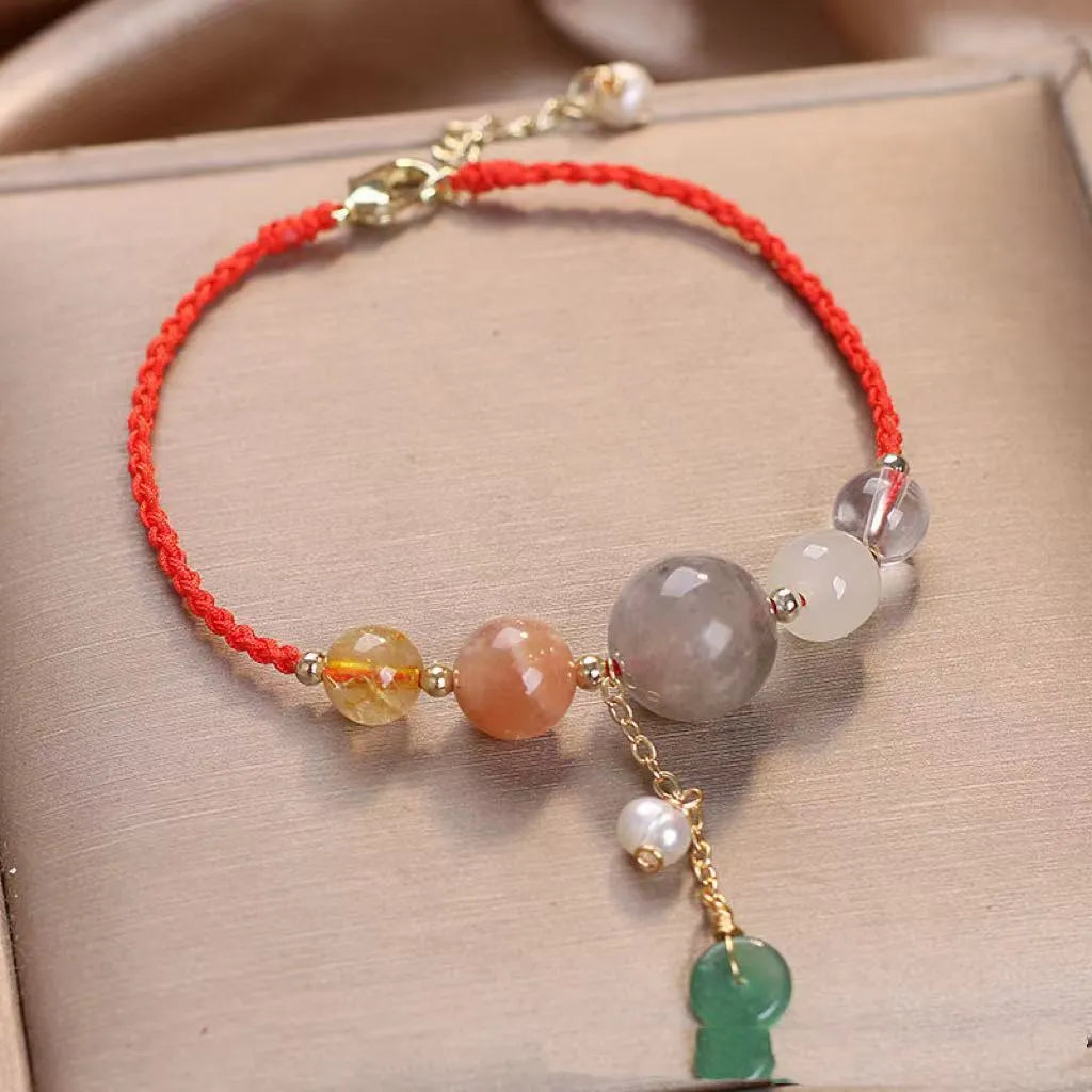 Women's hand-woven bracelet with crystal and sequins on a peace buckle clasp, shown in red, green, and blue colours.