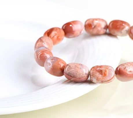 Natural cherry agate bracelet with barrel-shaped beads and a Ruyi design element on a wrist.