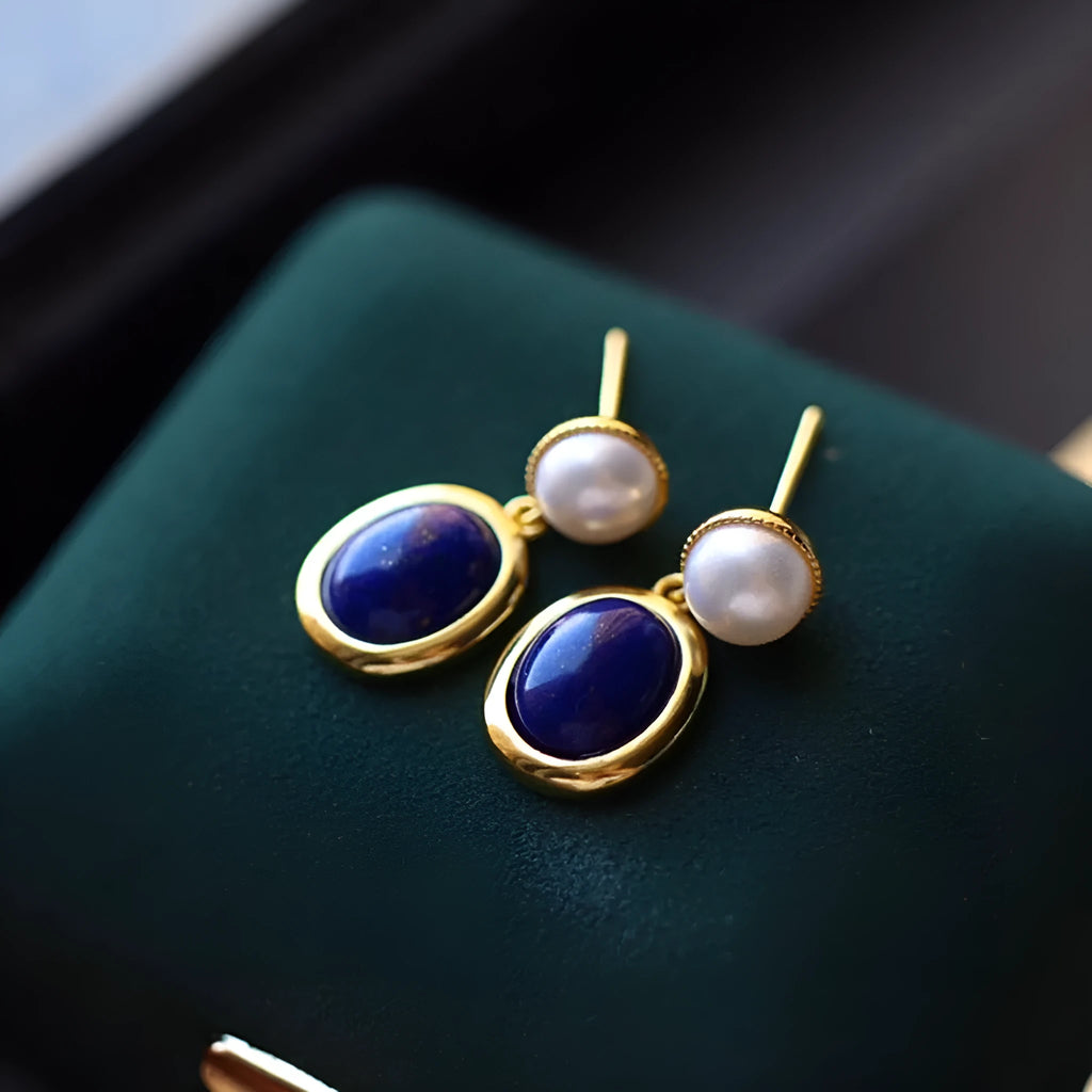A pair of simple 925 silver earrings featuring a blue lapis lazuli pearl and auspicious pattern detailing.