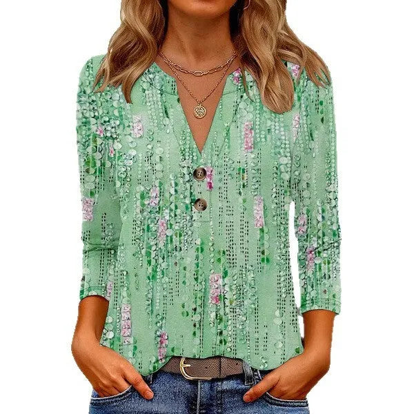 Woman wearing a loose-fit grey V-neck t-shirt with a colourful 3D geometric print, short sleeves.