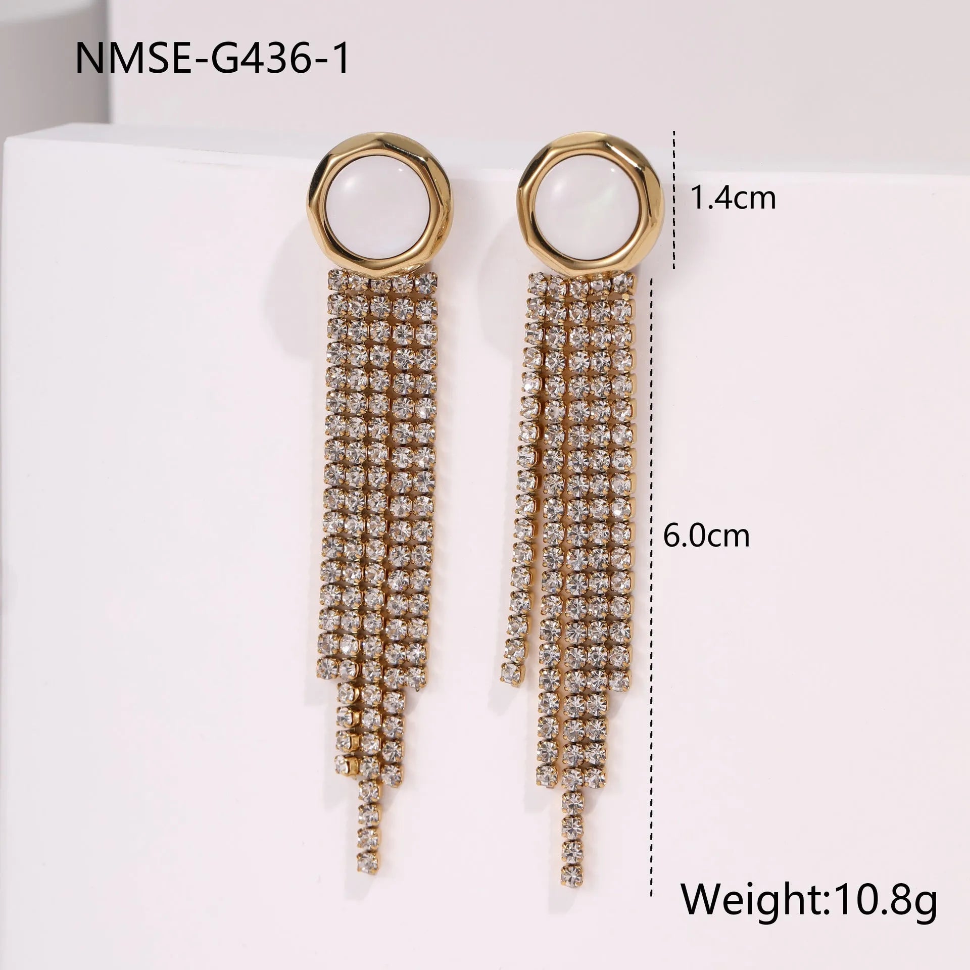 Close-up of a women's stainless steel earring with a heart shape and a dangling geometric tassel featuring diamond and star details.
