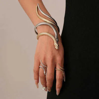 Gold tone snake-inspired bracelet and ring set with exaggerated twisted winding design on white background