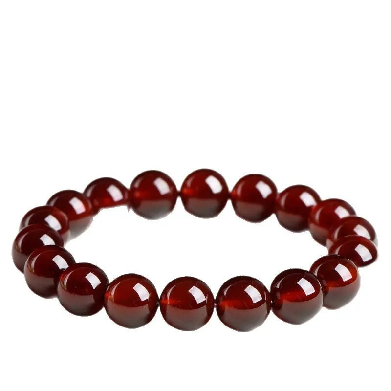 Natural orange red garnet crystal ball bracelet with a gold-toned Ruyi charm on a white background.