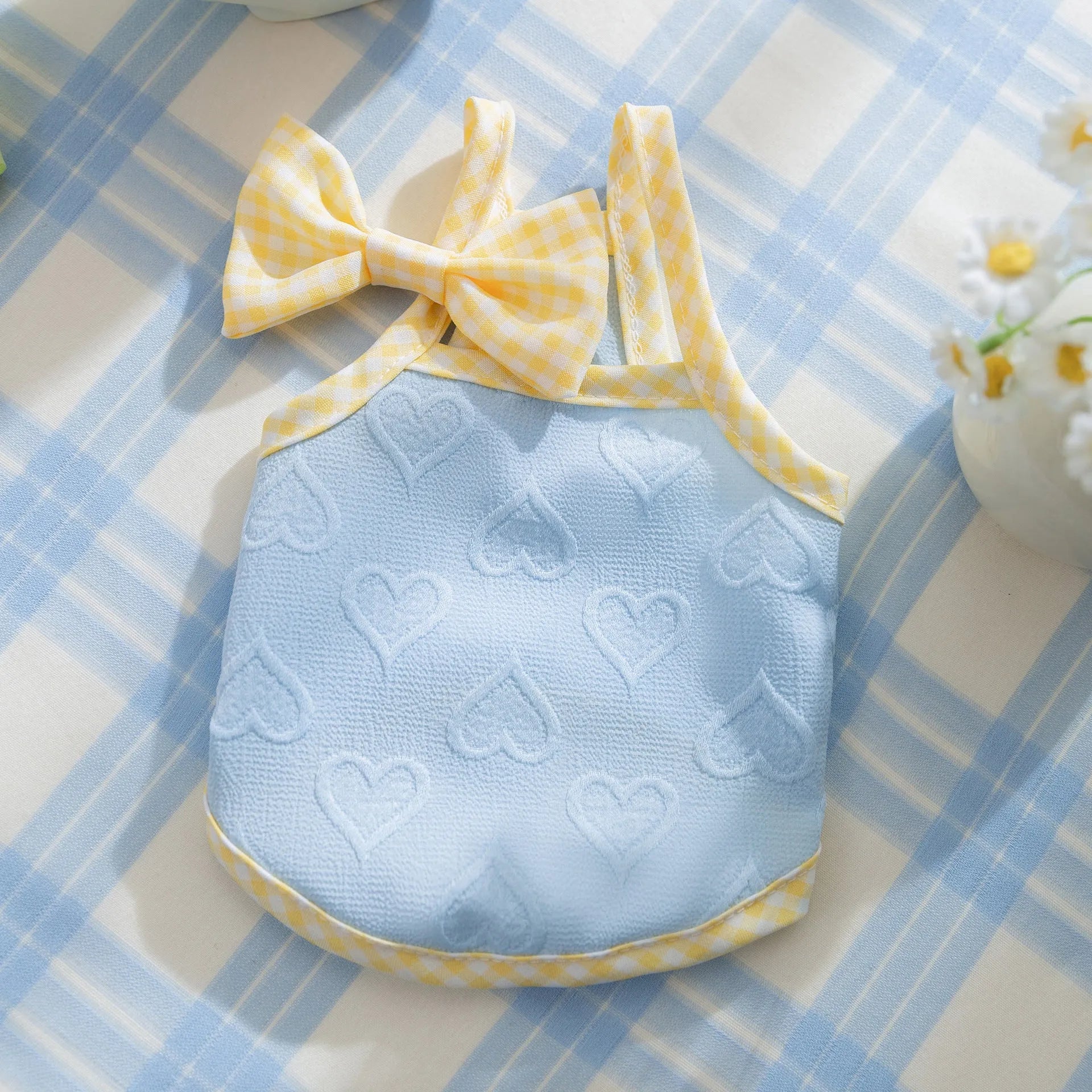 Small dog wearing a blue elastic vest with heart relief texture and bow suspenders.