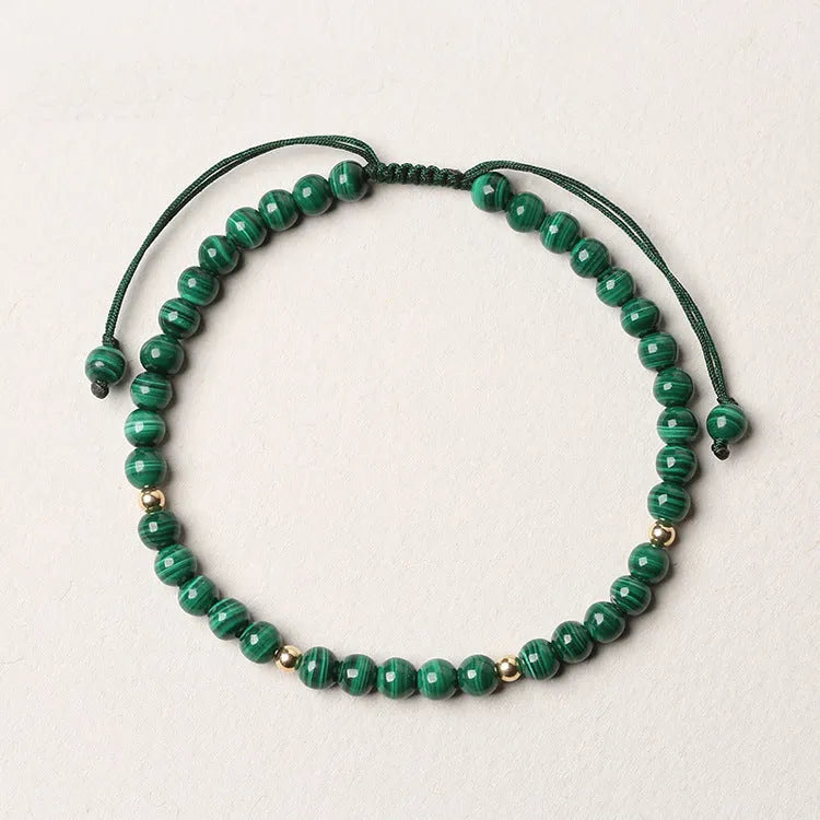 Women's malachite and gold bead bracelet with animal zodiac charm on woven strap.