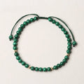 Women's malachite and gold bead bracelet with animal zodiac charm on woven strap.