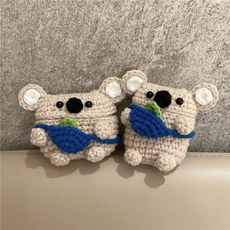 Hand-knitted grey koala bear backpack design earphone cover for Apple AirPods on a table.