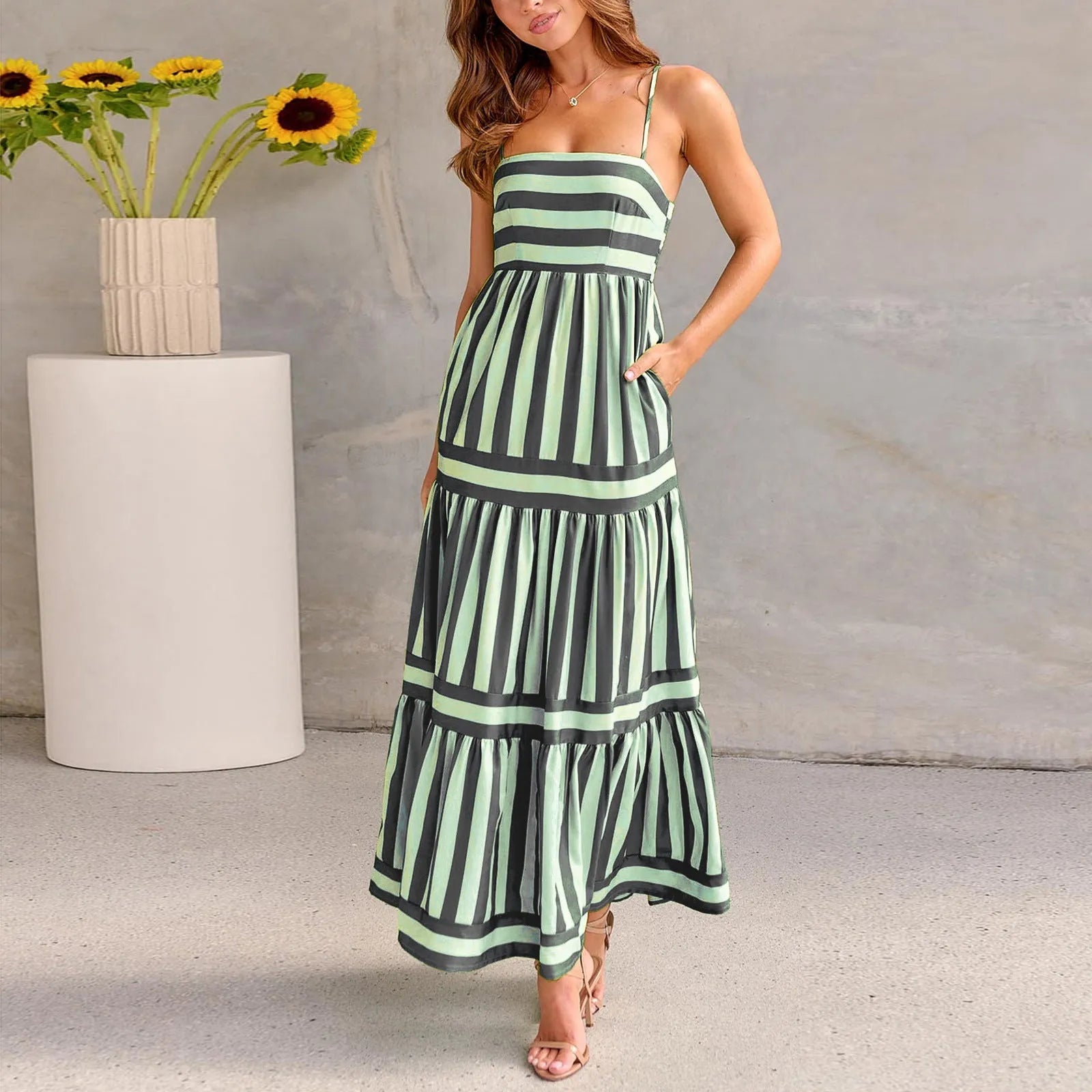 Woman wearing a striped backless suspender long dress with a square neck and side pockets.