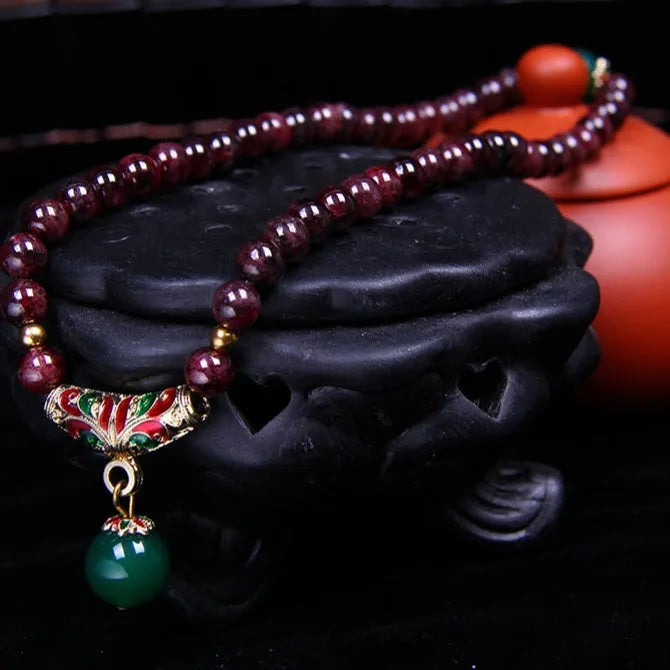 Natural red garnet 7mm bracelet with a golden toad charm on wrist, showing double ring clasp.