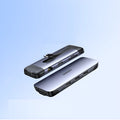 Silver USB laptop docking station with HDMI, USB 3.0, and charging ports on a desk.