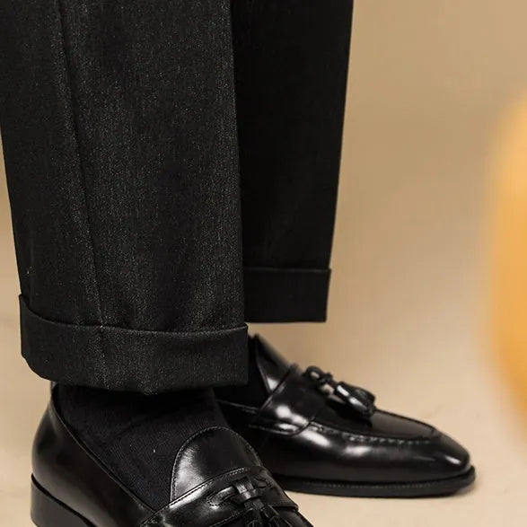 Men's black genuine leather tassel loafers with a polished finish and rubber sole.