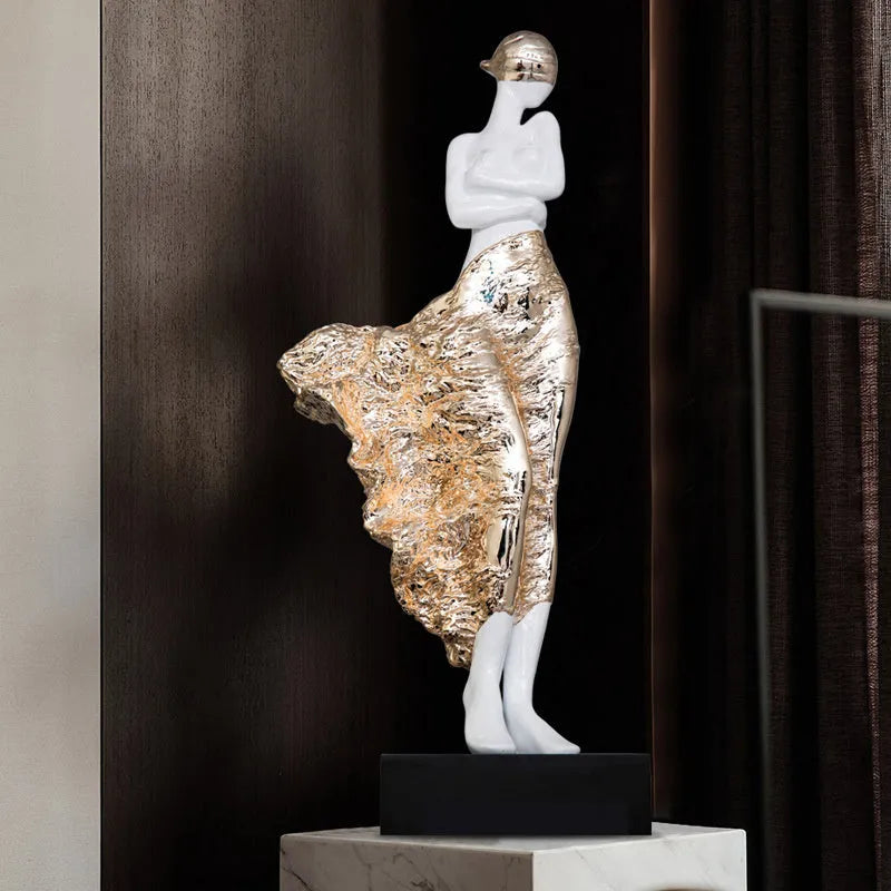 Tall modern sculptured character ornament in a metallic rose gold finish on a table.