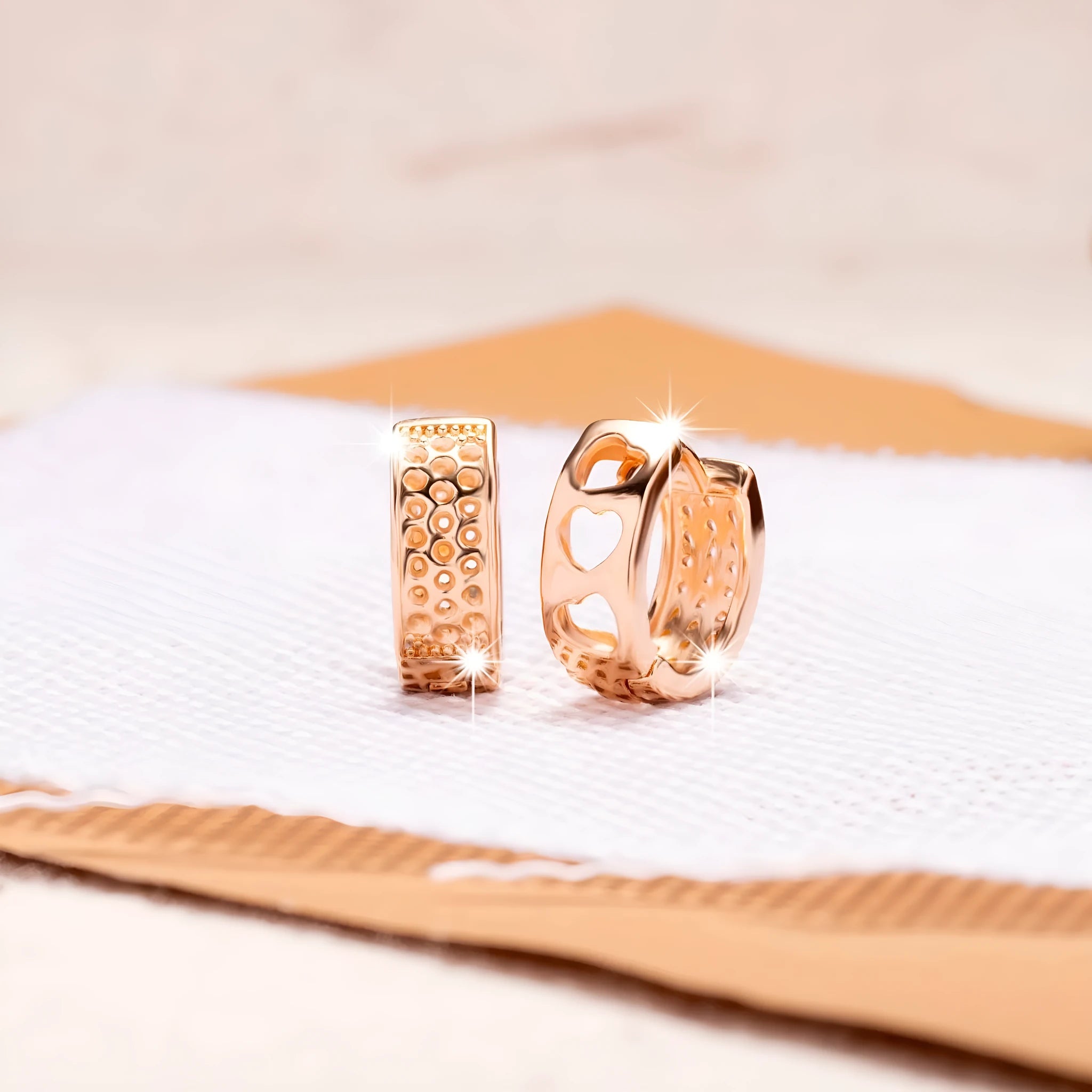 A pair of rose gold hollowed-out heart earrings on a white background, showing three-dimensional openwork detail.