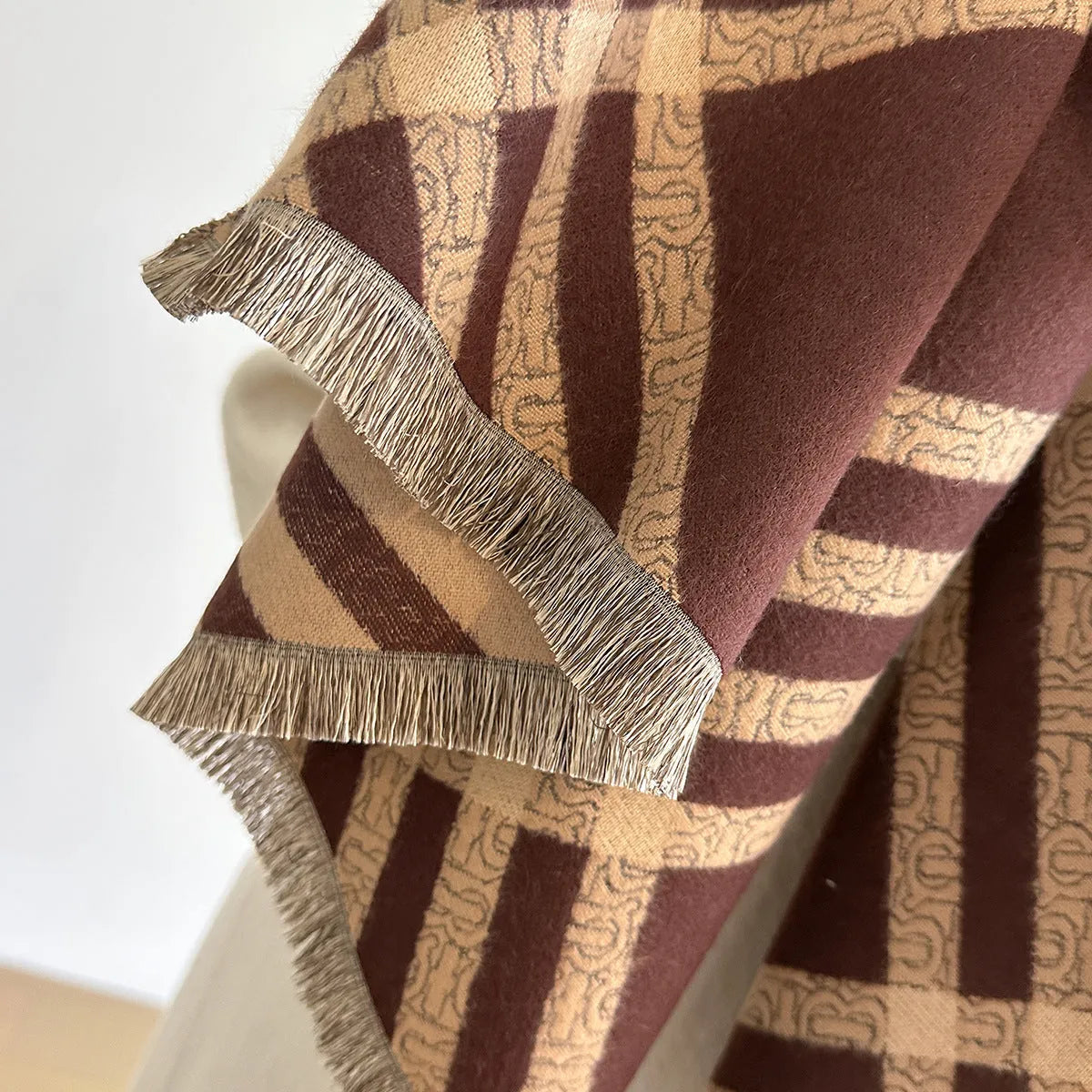Mid-length brown imitation cashmere winter scarf with tassel trim laid flat.