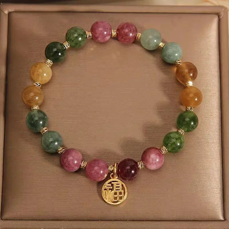 Natural colour tourmaline bracelet with silver electroplated flower and fu character charms on a geometric beaded band.