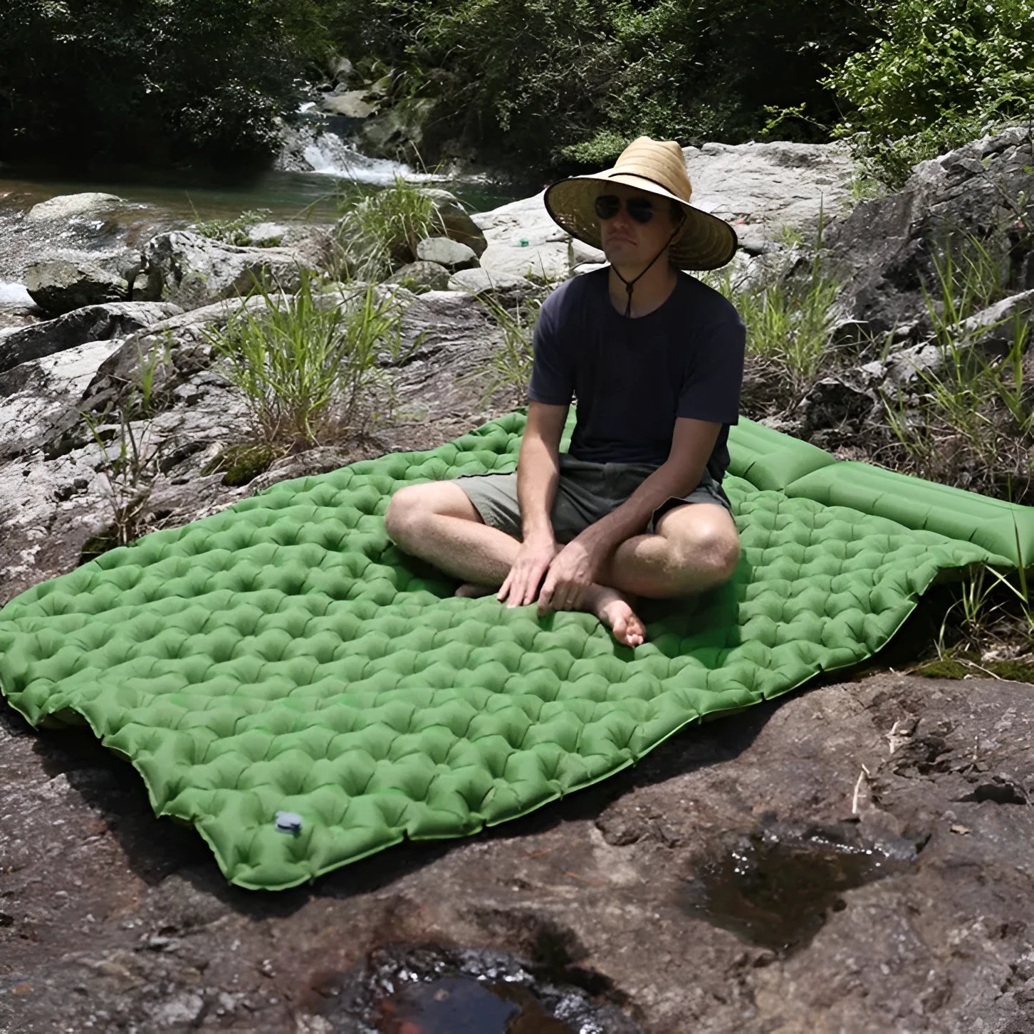 Dark blue double air mattress with built-in pump inflated on a floor, showing integrated pillow.