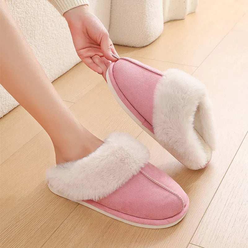 Brown plush indoor slippers for women with a non-slip PVC sole on a wooden floor.