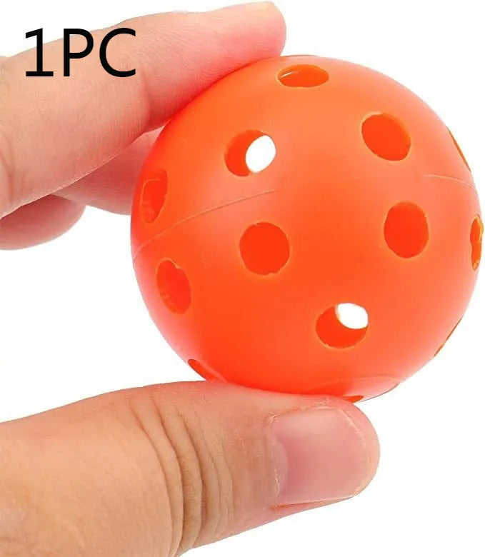 Multi-colour golf practice balls with 26-hole design on a green surface next to a net pocket.