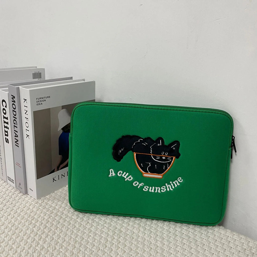 Embroidered animal design laptop sleeve in polyester, shown next to a laptop.