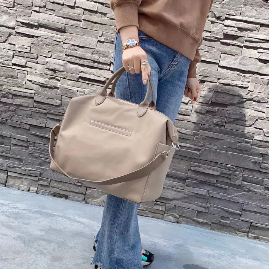 Black waterproof nylon shoulder bag with leather detailing showing large main compartment