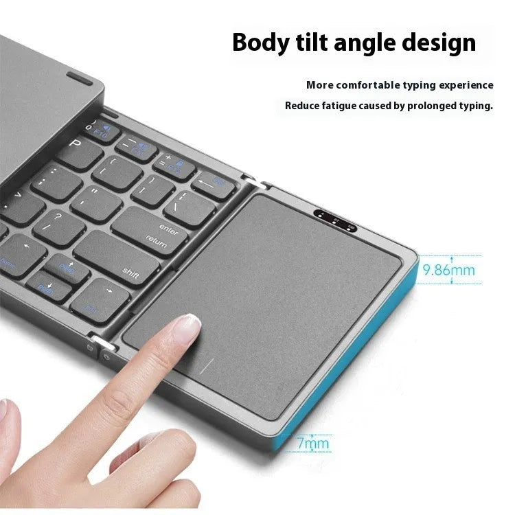 Three folding wireless Bluetooth keyboard with touch pad in black, open on a table next to a mobile phone