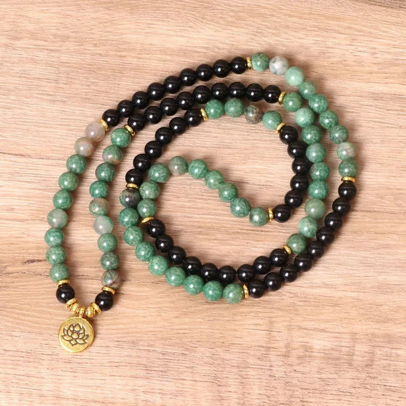 Green and black alloy beads on an elasticated bracelet, shown on a wrist.