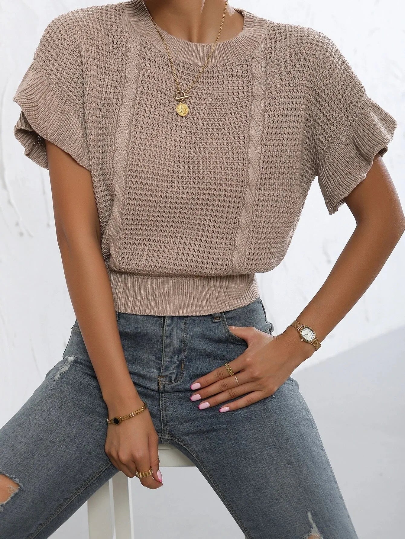 Knitted loose pullover sweater with ruffled short sleeves and a 3D twisted string pattern, shown in a neutral colour.