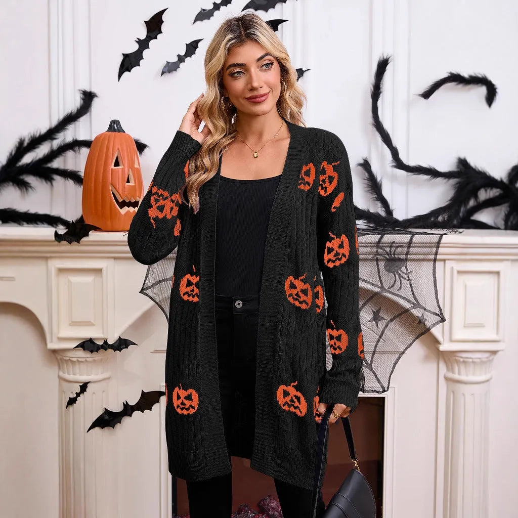 Women's black cardigan with orange pumpkin head jacquard knit pattern, shown as a medium-length coat.