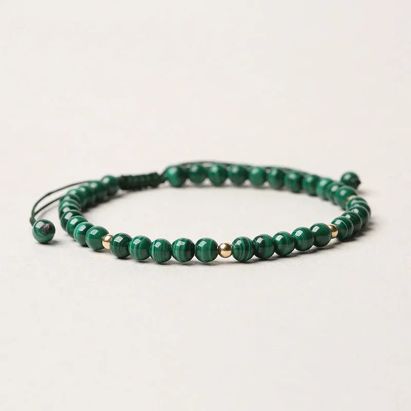 Women's malachite and gold bead bracelet with animal zodiac charm on woven strap.