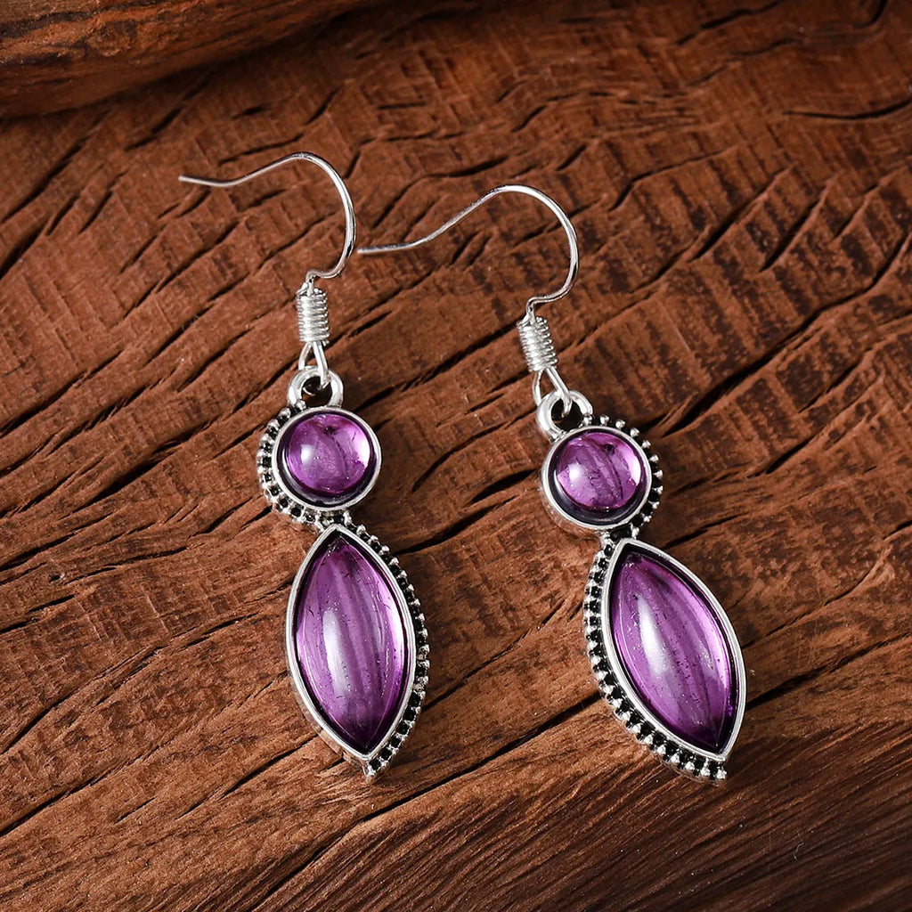 A pair of vintage-style geometric drop earrings with black and purple electroplated pendants on a white background.
