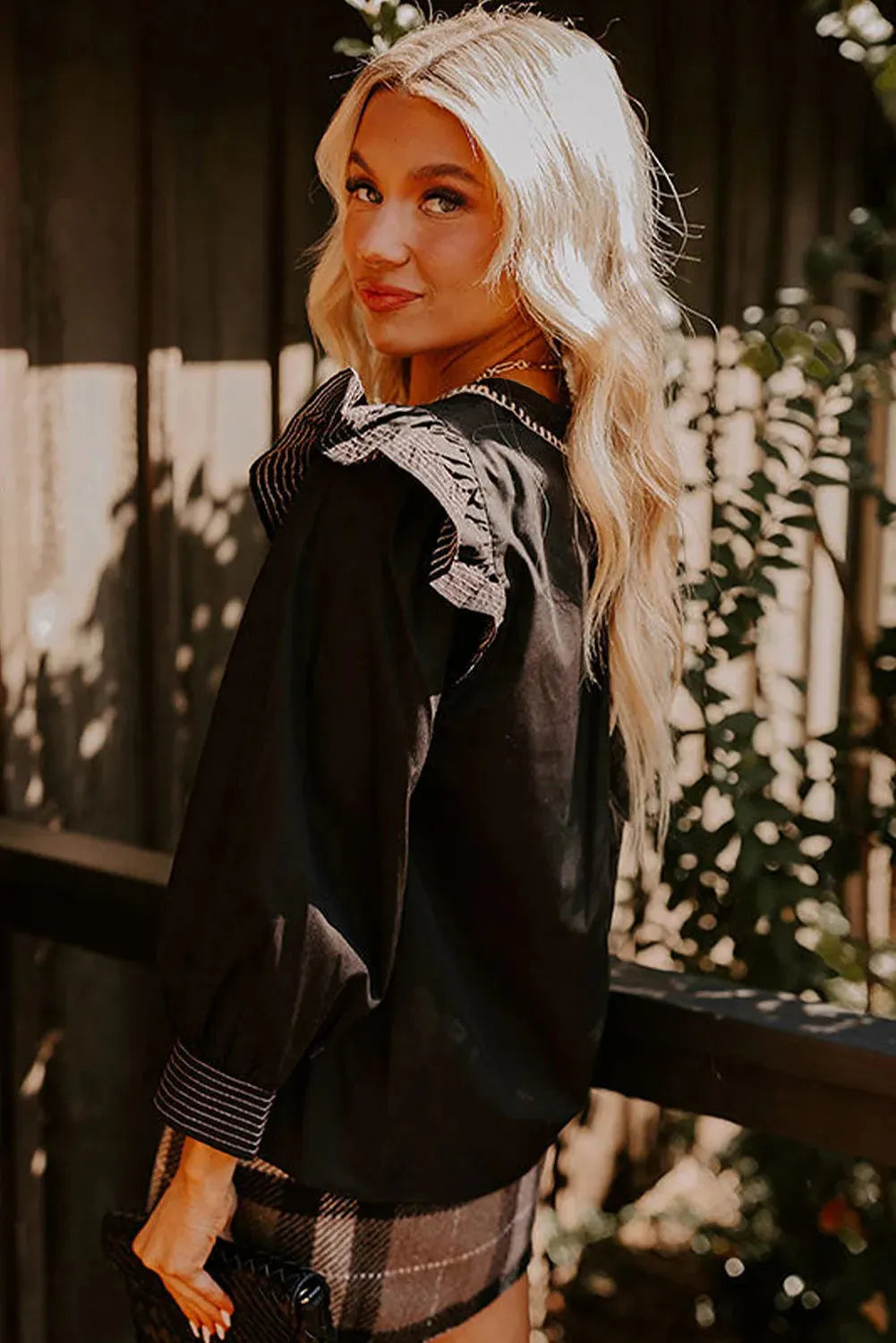 Black V-neck long sleeve blouse with ruffle trim and contrast colour stitching.