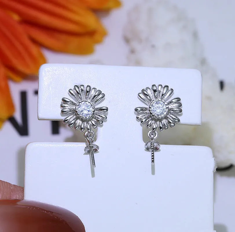 A pair of Baroque-style floral earring frames made of sterling silver, featuring a small integrated ring holder, presented without pearls.