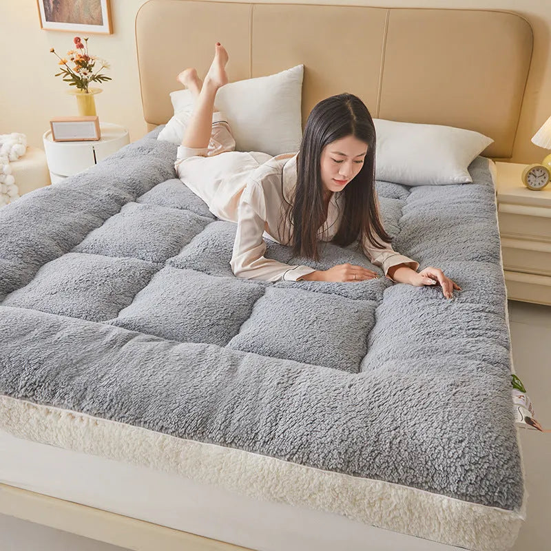 Lambswool mattress cushion with velvet cover in grey and white edge, on a bed