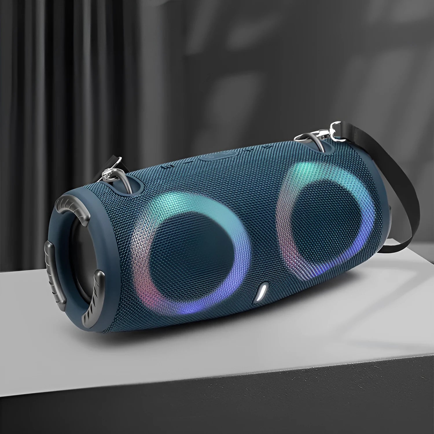 Cylindrical War Drum Bluetooth speaker with glowing RGB lights, a black metal grille, and a carrying strap on a wooden table.