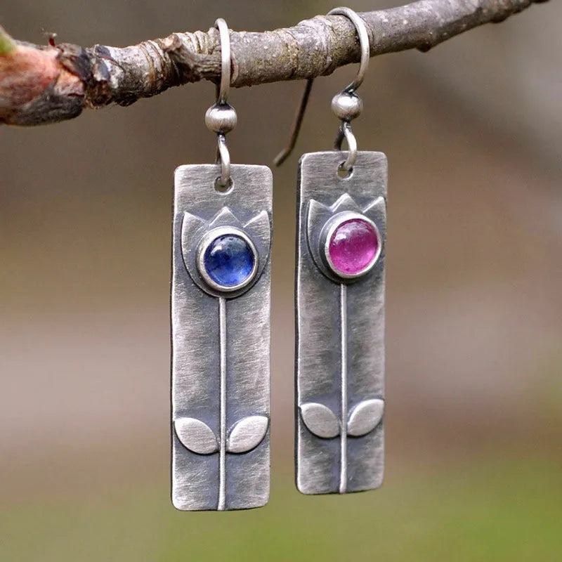 Pair of antique finish red sapphire geometric ellipse earrings with retro style on a white background.