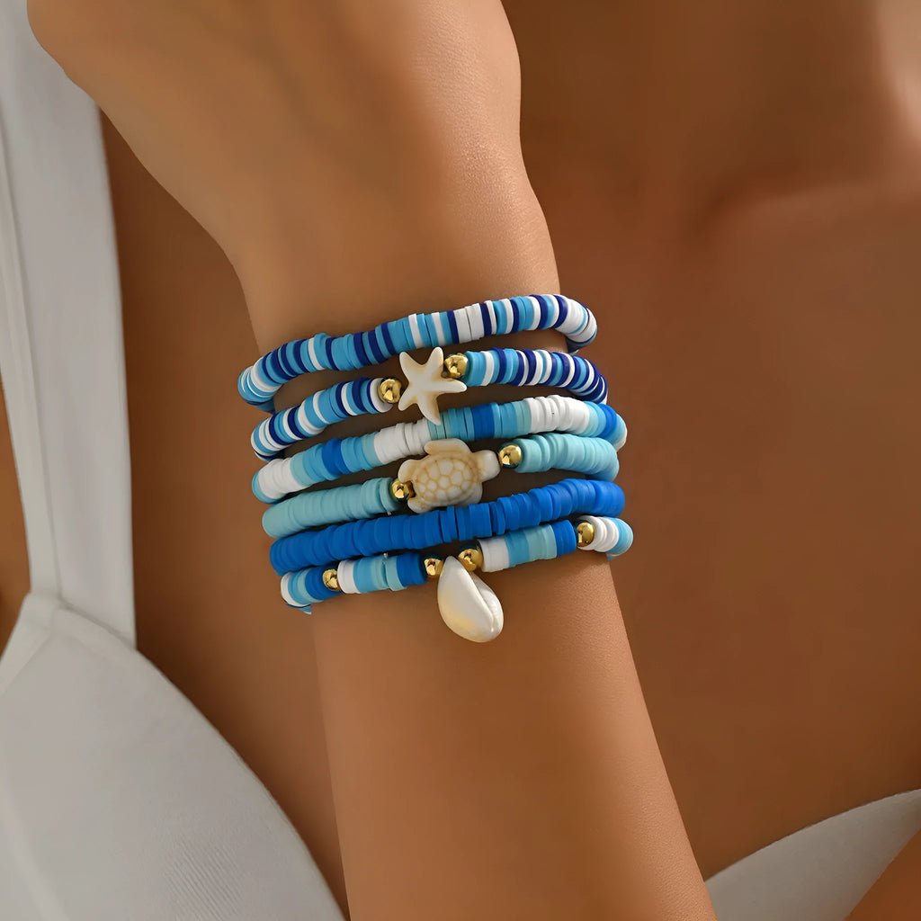 Six handmade Bohemian blue polymer clay bracelets with shell designs and geometric shapes arranged together