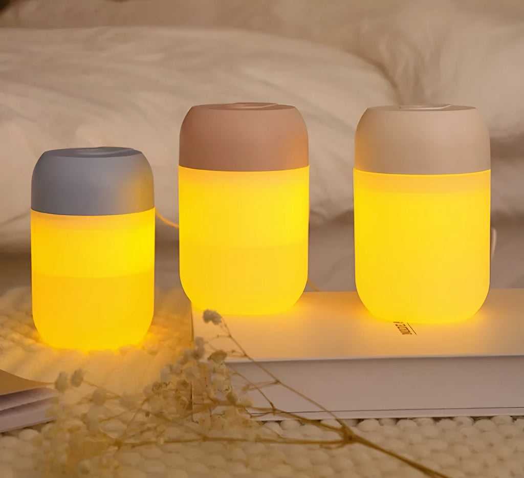 White cylindrical mini humidifier with USB cable and aromatherapy tray on a wooden desk.