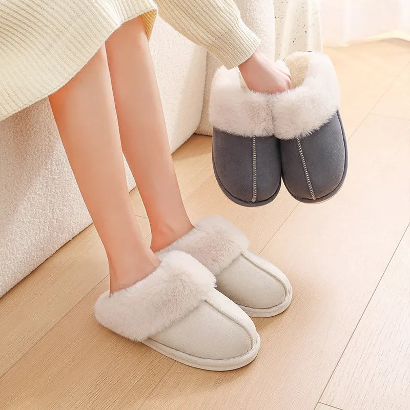 Brown plush indoor slippers for women with a non-slip PVC sole on a wooden floor.